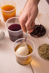 Hand dip spoon with egg into a jar of dye