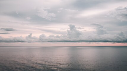 A cloudy sky and sea with lots of clouds. Soft, overcast clouds stretching across the horizon. The atmosphere is calm and moody, capturing the serene yet dramatic beauty of the cloudy seascape.