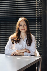 Portrait of a beautiful woman in a white shirt sitting at the table