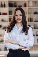 Confident young businesswoman with crossed arms in modern office interior