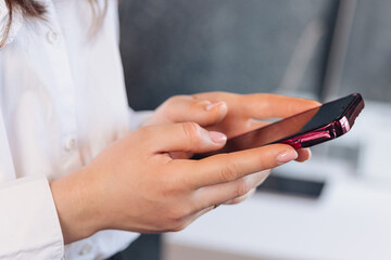 Female hands typing a message on a smartphone in a business setting