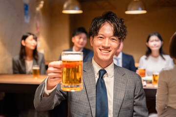 居酒屋でビールの乾杯をするサラリーマンの男性