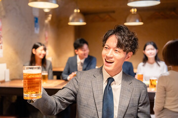 居酒屋でビールの乾杯をするサラリーマンの男性