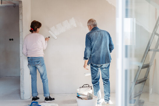Senior husband and wife repainting the walls.