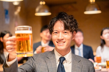 居酒屋でビールの乾杯をするサラリーマンの男性