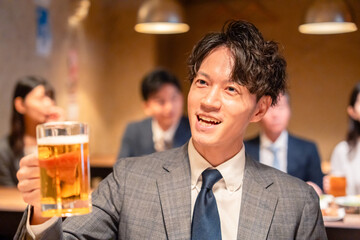 居酒屋でビールの乾杯をするサラリーマンの男性