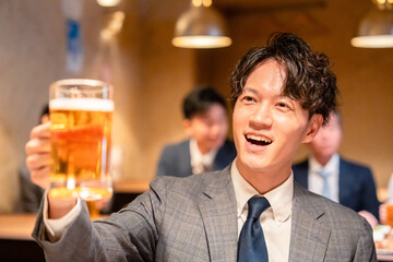 居酒屋でビールの乾杯をするサラリーマンの男性