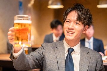 居酒屋でビールの乾杯をするサラリーマンの男性
