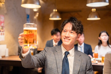 居酒屋でビールの乾杯をするサラリーマンの男性