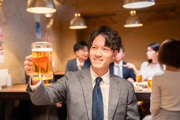 居酒屋でビールの乾杯をするサラリーマンの男性
