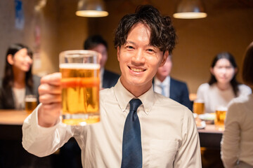 居酒屋でビールの乾杯をするサラリーマンの男性