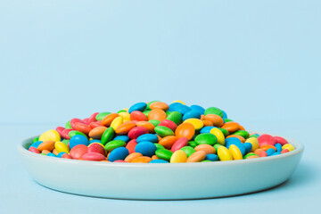 Multicolored candies in a bowl on a colored background. birthday and holiday concept. Top view with copy space