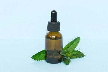 Natural Mint Essential Oil in a Glass Bottle. organic cosmetics with herbal extracts of mint on colored background