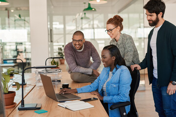 Diverse group of smiling businesspeople working together around a laptop