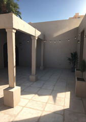 entrance to the city, stone walls and columns decorated by white tile flooring and string lights with plants as accents