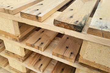 Stack of wooden pallets in a warehouse. Industrial background for cargo transport and logistics. Storage and shipping materials texture. Supply chain and distribution concept.