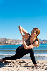 Woman practicing yoga on beach, enjoying breathing exercises and meditation
