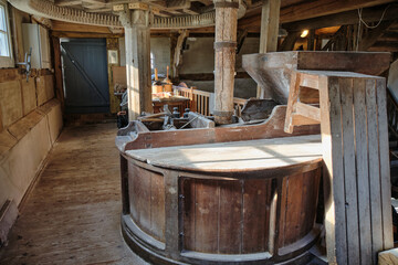 Millstone and wooden gear mechanism inside historic mill © VeugerStock