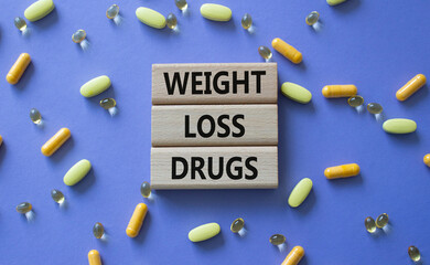 Medicine symbol. Concept words Weight Loss Drugs on wooden blocks. Beautiful purple background with...