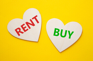 Rent or Buy symbol. Concept word Rent or Buy on wooden hearts. Beautiful yellow background. Business and Rent or Buy concept. Copy space