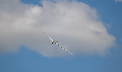 Segelflugzeug in der Luft vor blauem Himmel und weiße Wolken