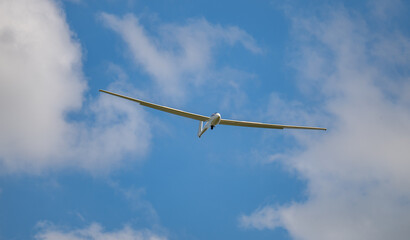 Segelflugzeug in der Luft vor blauem Himmel und weiße Wolken