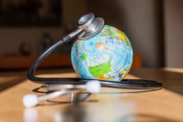 International Health Care Concept: Stethoscope Wrapped Around World Globe Indicating Global Medical...