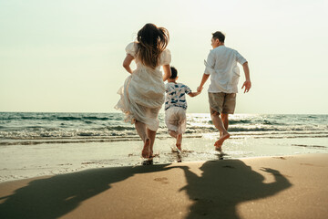 On vacation, travel, or a long weekend, spend time together with family and have fun and happiness by running hand in hand on a beautiful beach with sunset light.