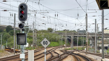 Railway tracks with a red signal light, transportation infrastructure, overcast sky, travel,...