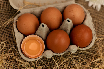 Organic brown eggs in an egg carton. Eggs in a box on straw. Broken Egg
