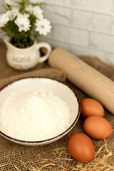 Baking products - flour, eggs. Flour and eggs on the table close-up