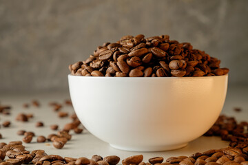 Coffee beans piled high in a white bowl with scattered beans around