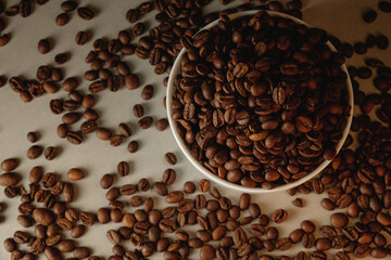 Rich aroma of roasted coffee beans spilling from a bowl on a flat surface
