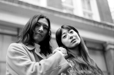 Young couple posing with building in background in monochrome analog style