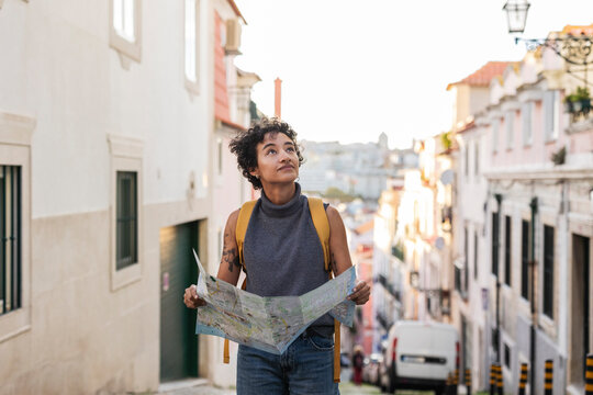 Tourist exploring lisbon using map and looking up at buildings