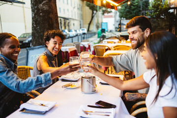 Happy friends toasting with water at outdoor restaurant table