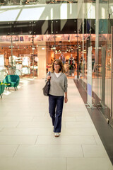 Obraz premium Full length of mid aged woman walking in a shopping mall