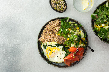 Delicious healthy breakfasts, green buckwheat with fried egg and spinach and red salmon fish, mix salad with fresh herbs and peppers and seeds, healthy balanced breakfast with fats, fiber and protein