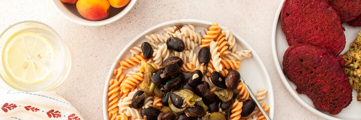 Savor gluten-free pasta with baked beans and zucchini, alongside beet pancakes with sunflower seed hummus. This vegetarian feast is a delicious and nutritious choice, banner