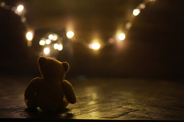 Lonely Teddy Bear with Fairy Lights in Cozy Dim Lighting for Conceptual Photography © alexkich