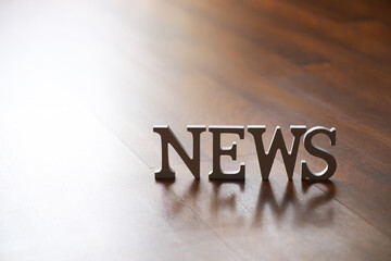 Metallic News Text on Wooden Surface with Sunlight Reflection - Modern Communication Concept