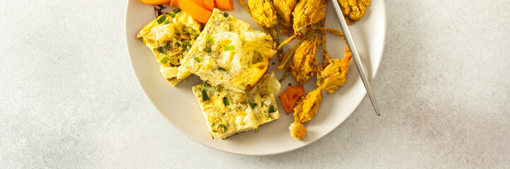 This flavorful meal includes fried zucchini flowers in golden batter, a tender cauliflower omelette with stewed peppers ideal for a healthy diet, banner