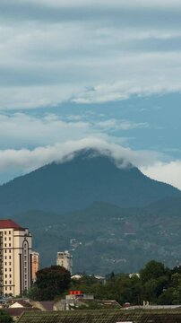 Vertical video - Timelapse of clouds rolling over the mountain top in the afternoon in Bandung, Indonesia