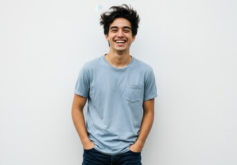 A young man smiling broadly with hands in his pockets against a white background in a studio shot
