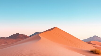 The warm glow of the setting sun illuminates smooth sand dunes, creating gentle shadows and highlighting the natural curves of the desert landscape in a serene atmosphere