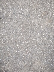 A close-up, top-down shot of a gray asphalt surface with a rough texture.
