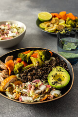 A hearty, balanced breakfast bowl with black quinoa, creamy avocado, roast chicken, sweet potatoes, zucchini, broccoli, and a fresh salad of cabbage and radish with chia and sesame seeds