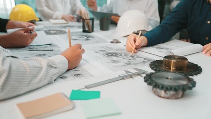 A collaborative group of engineers focused on technical drawings and tools in a modern workspace, promoting creativity and innovative solutions during a planning session. SACTR