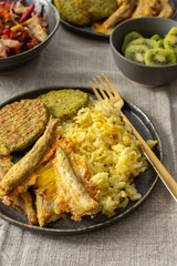 A healthy and flavorful breakfast with turmeric rice, ocean fish, broccoli pancakes, and a roasted vegetable salad, perfect for fueling your day with protein and healthy fats