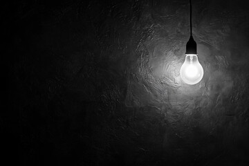 single light bulb hanging from a ceiling. The bulb is lit up and the room is dark